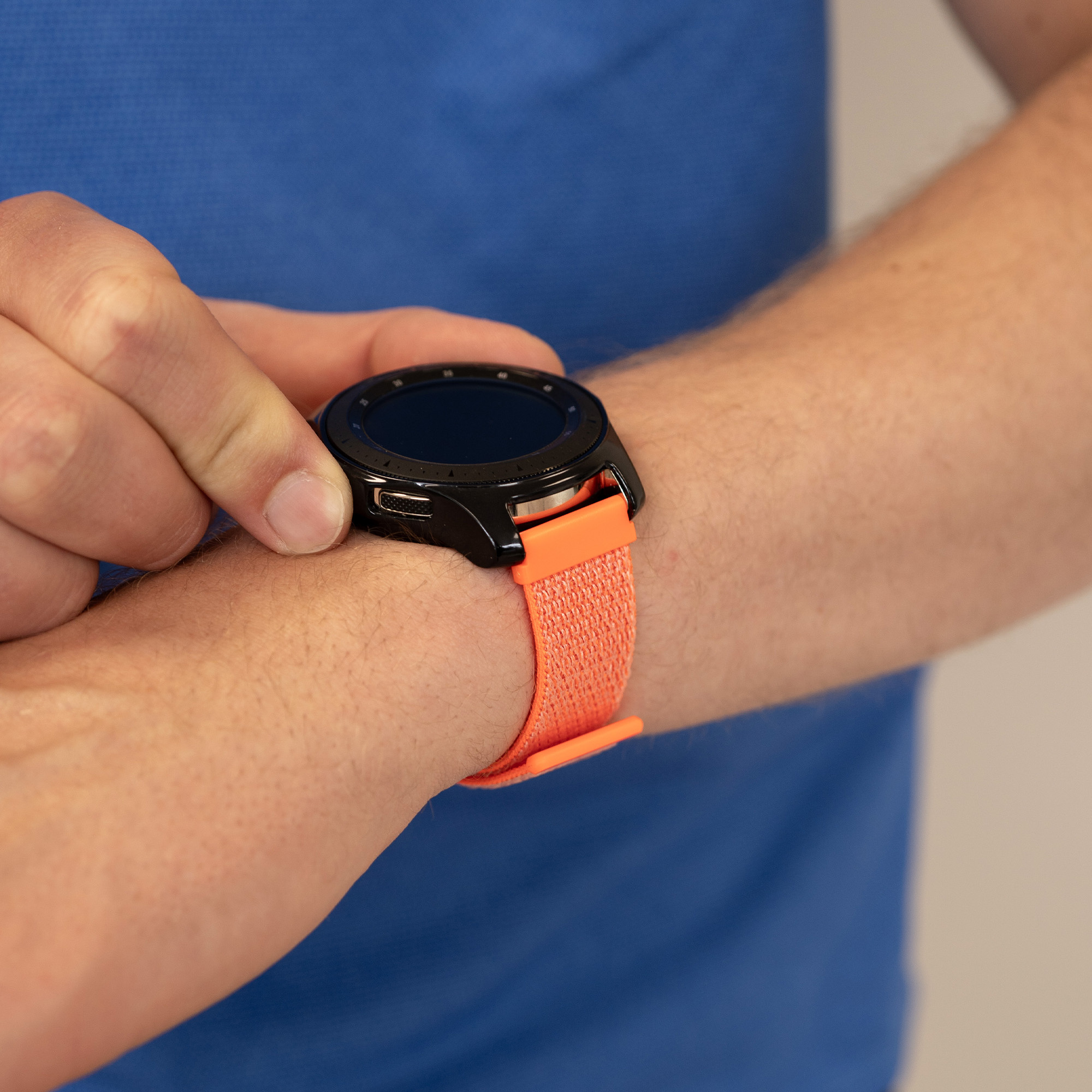Hand mit orangefarbener Uhr mit schwarzem Zifferblatt und schwarzer Lünette.