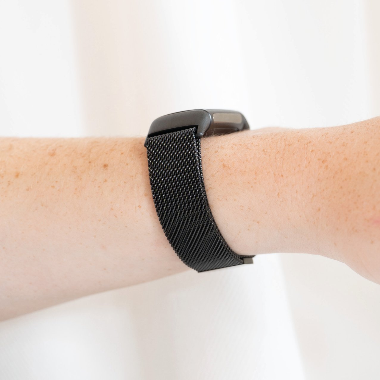 Das Handgelenk einer Person mit einer schwarzen Smartwatch. Die Uhr hat ein schwarzes Armband.