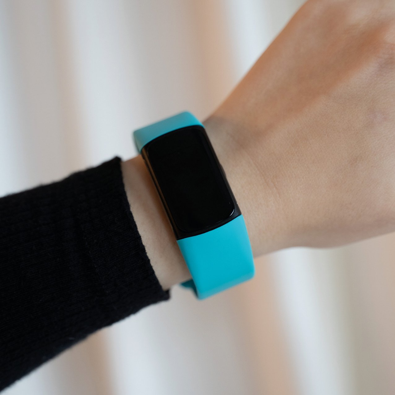 Eine schwarze Smartwatch mit blauem Armband am Handgelenk.