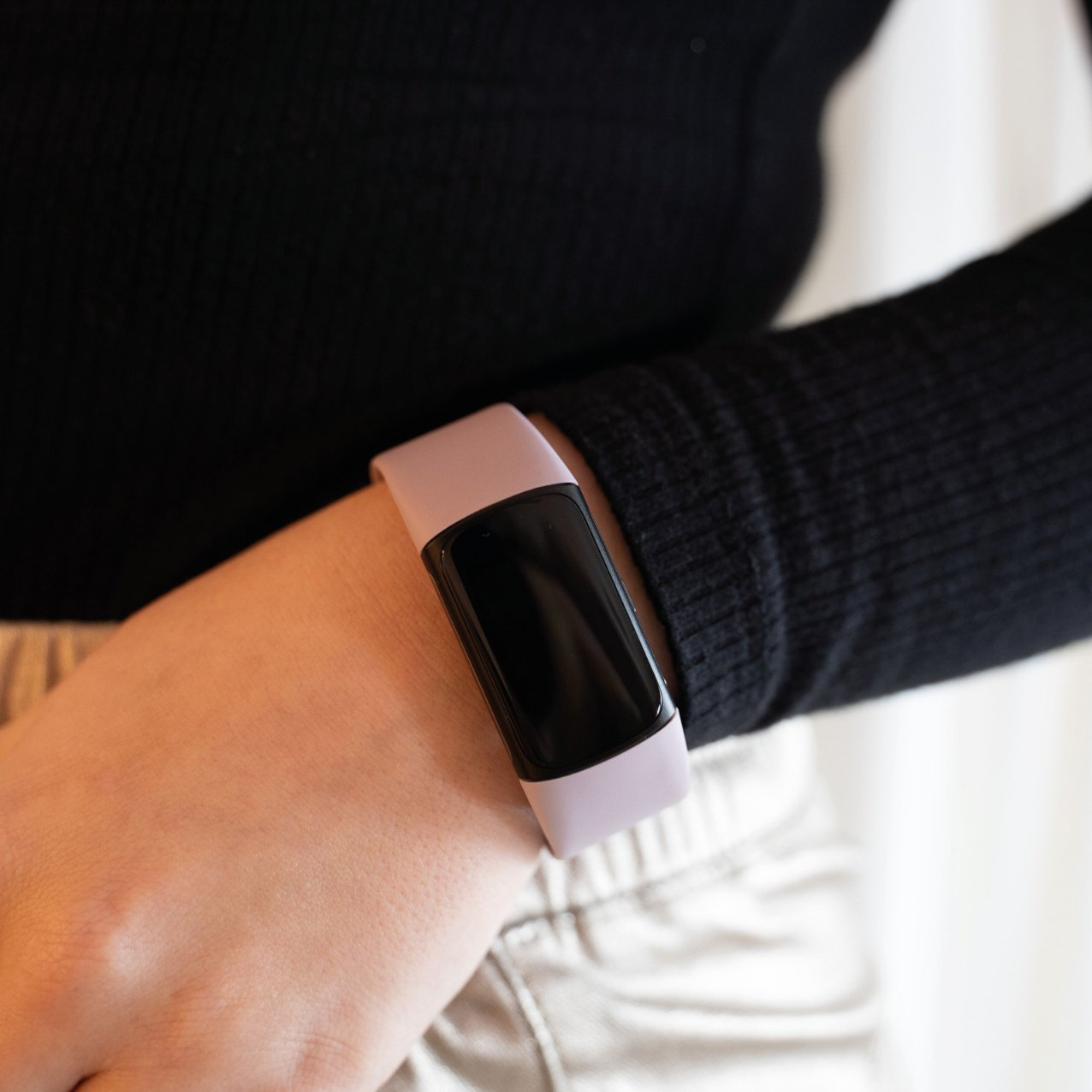 Handgelenk mit Fitnesstracker, lila Band, schwarzer Bildschirm.