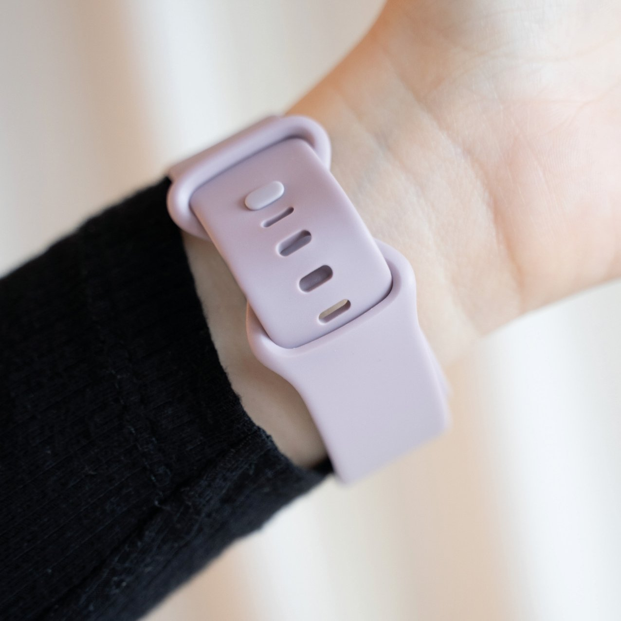 Ein Handgelenk mit einem hellvioletten Uhrenarmband, Nahaufnahme.