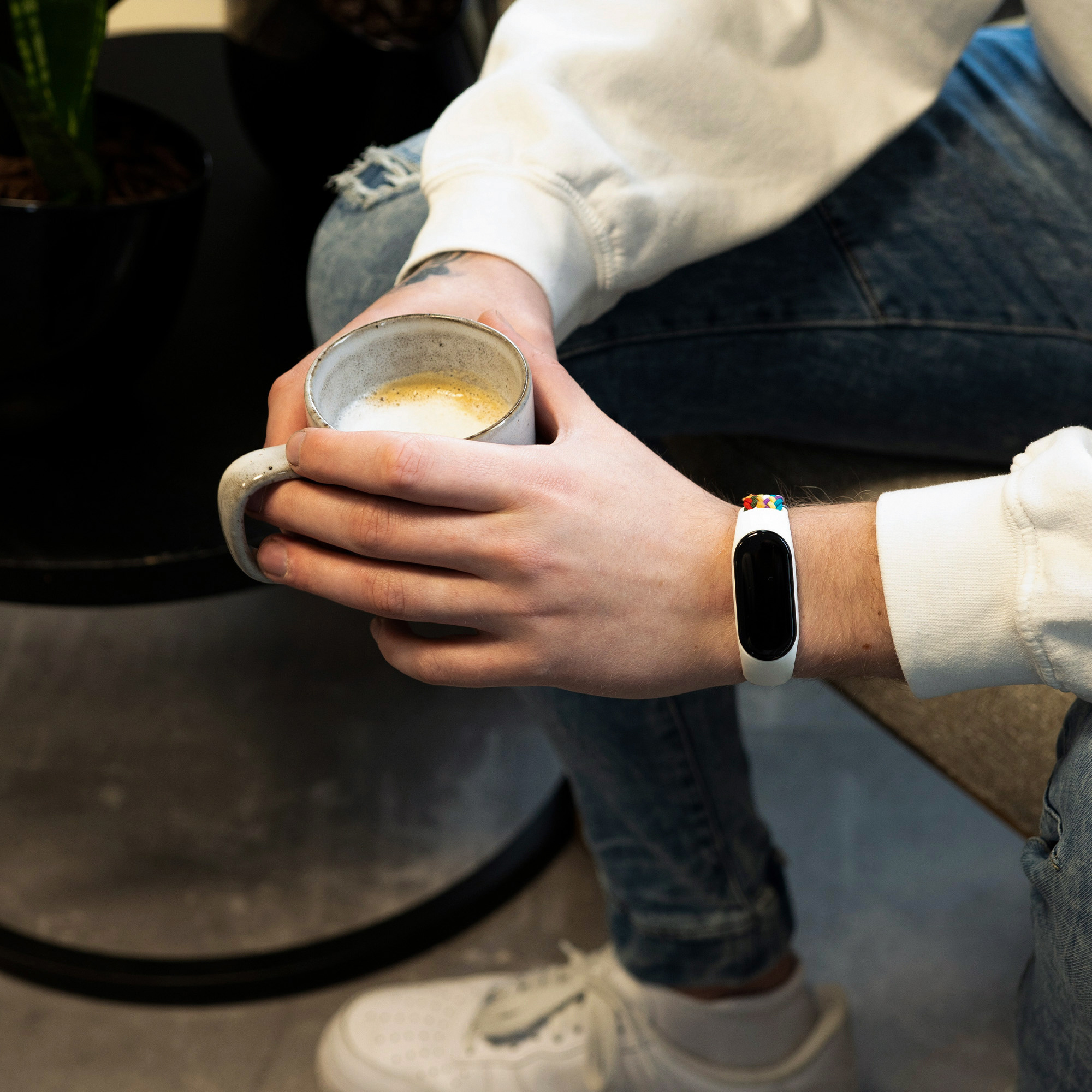 Mann mit Smartwatch, hält eine Kaffeetasse. Weiße und bunte Uhr.