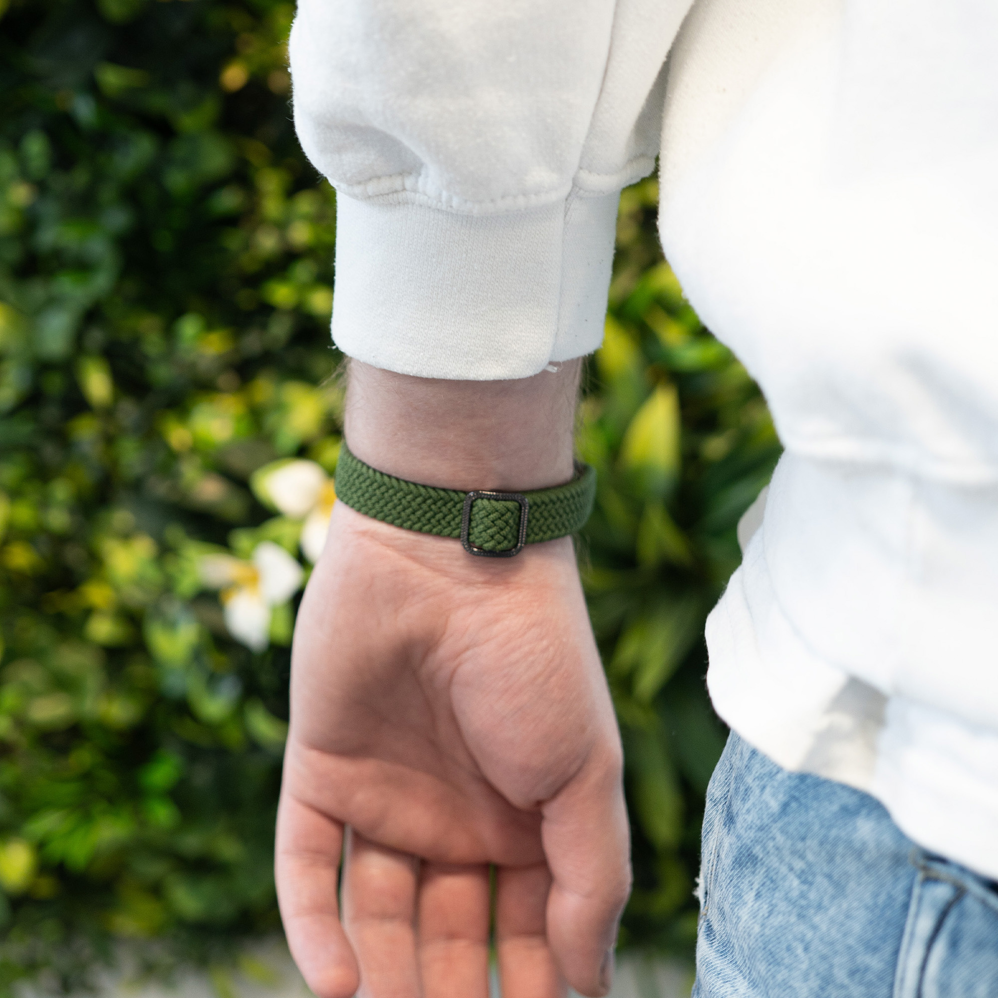 Das Handgelenk einer Person mit einem grünen Uhrenarmband.