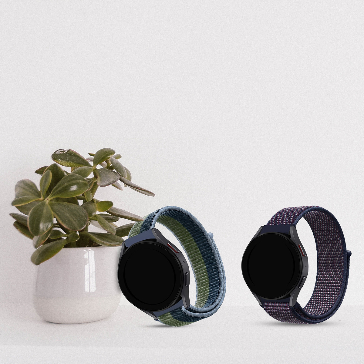 Zwei Smartwatches, eine mit grün-blauem Armband, die andere mit lila Armband.