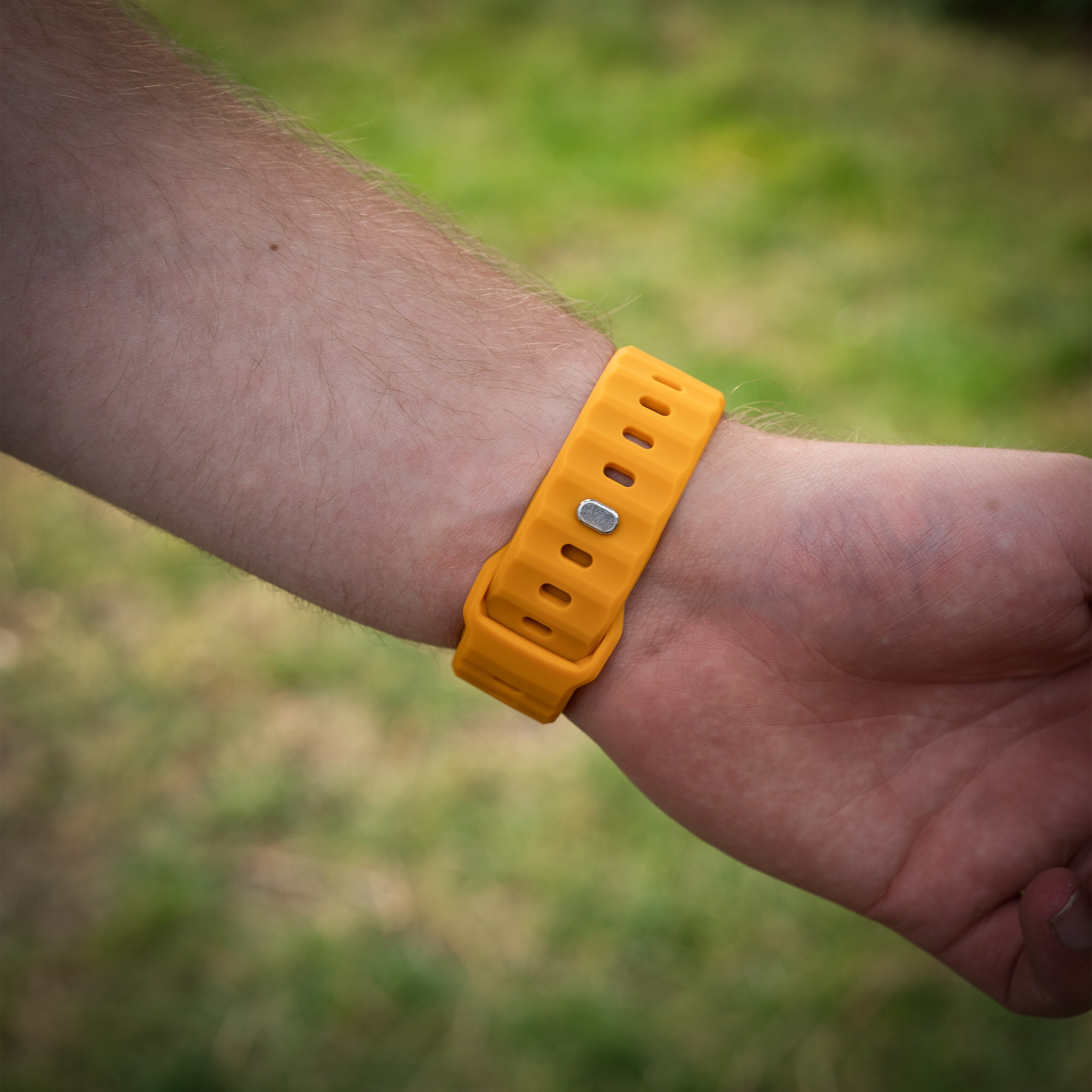 Die Hand einer Person mit einem orangefarbenen Uhrenarmband am Handgelenk.
