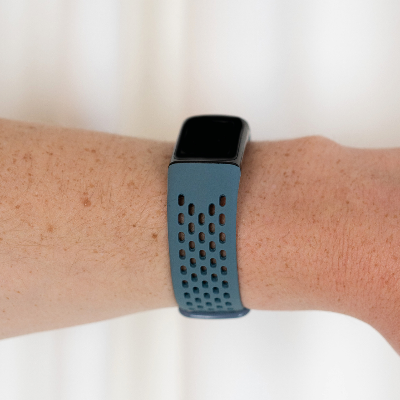 Eine Person trägt eine Smartwatch mit blauem Armband. Die Uhr ist an ihrem Handgelenk.