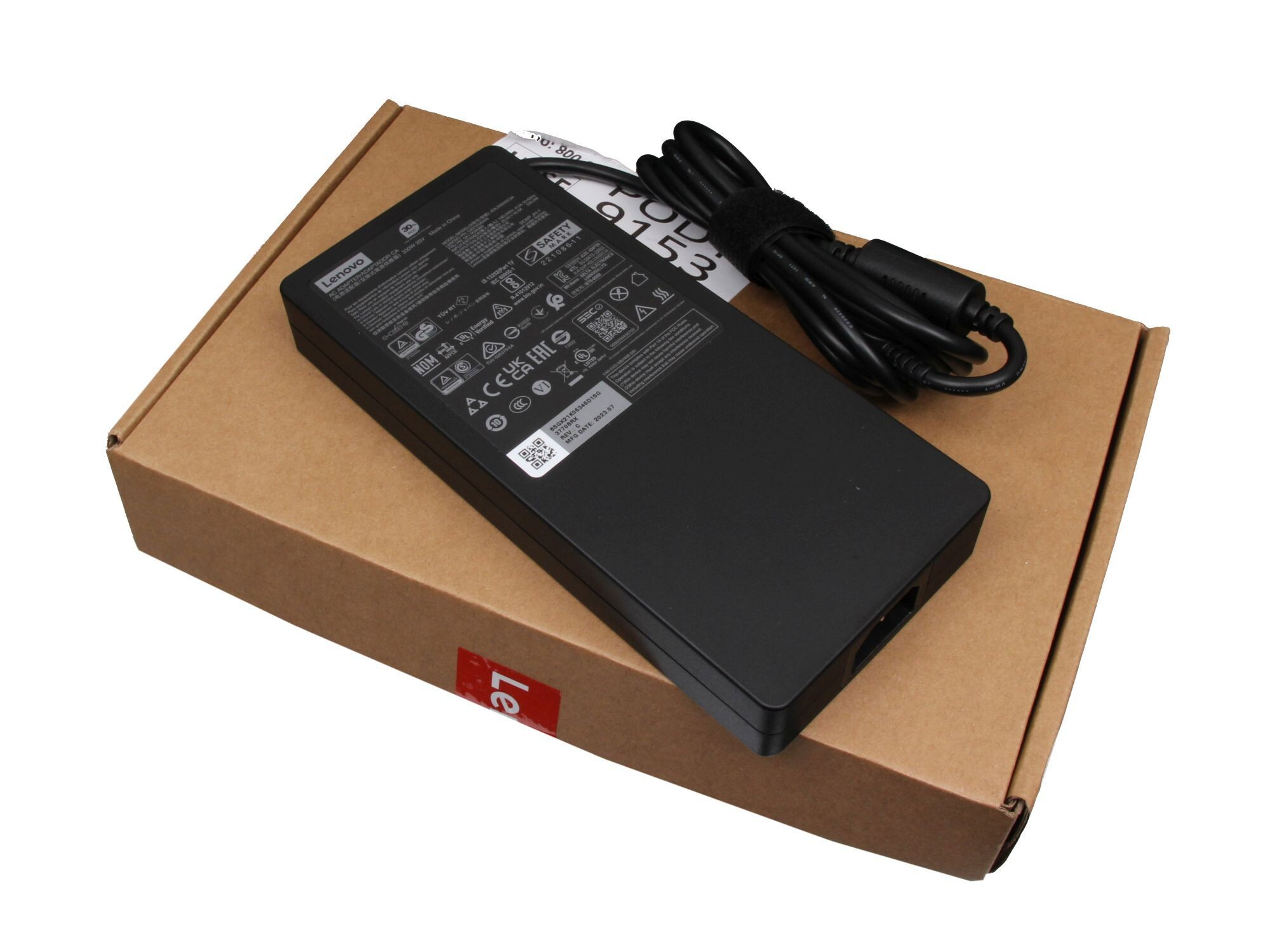Schwarzes Lenovo Laptop-Ladegerät auf einer braunen Box. Weißer Hintergrund.