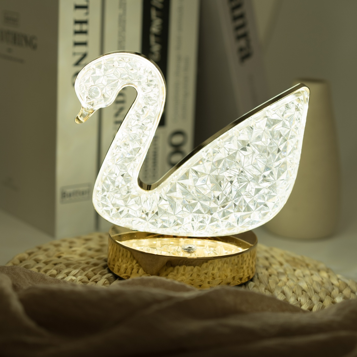 Una lámpara con forma de cisne con base dorada. El cuerpo del cisne está iluminado y facetado.