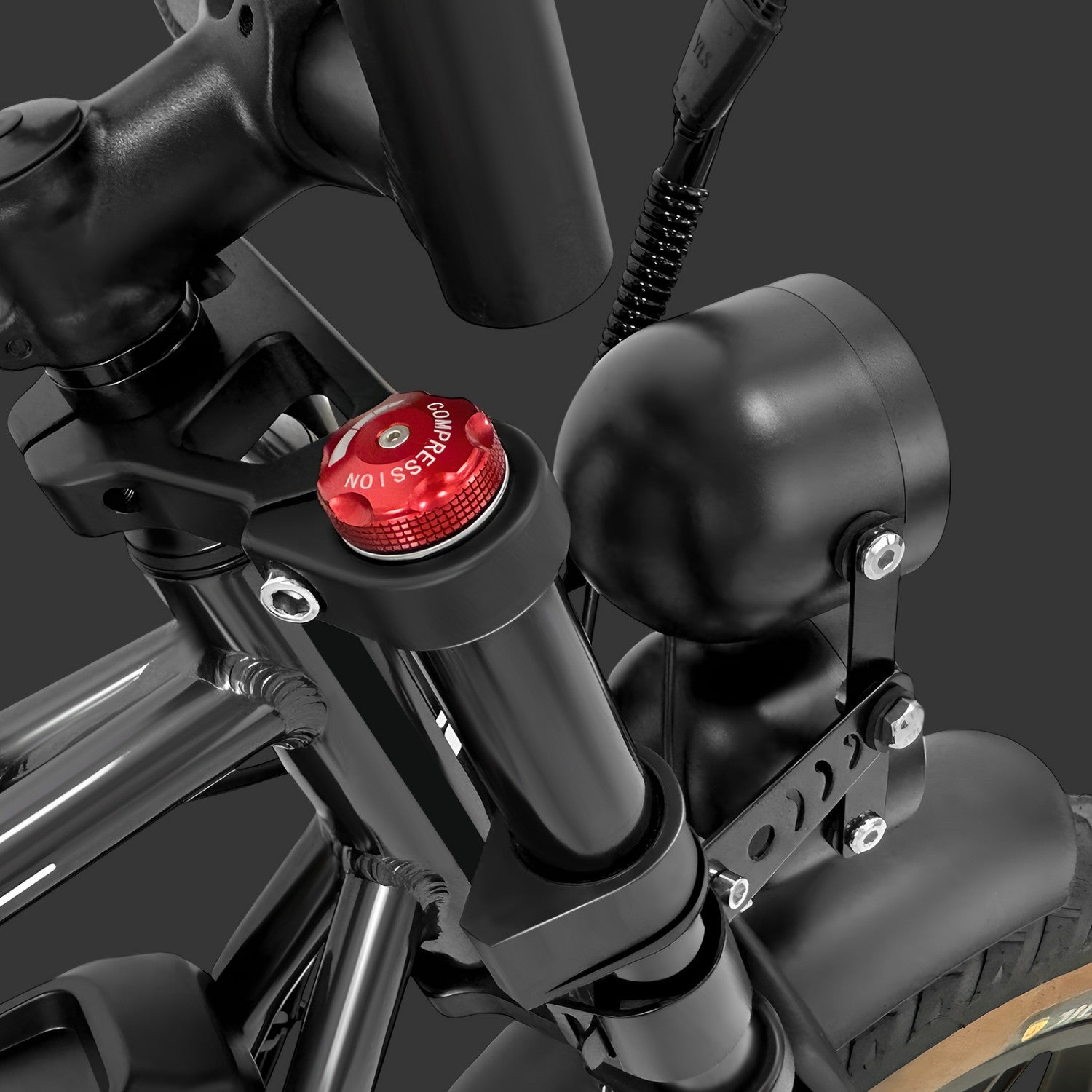 Primo piano di un componente di motocicletta nero con un tappo di compressione rosso e un faro nero.