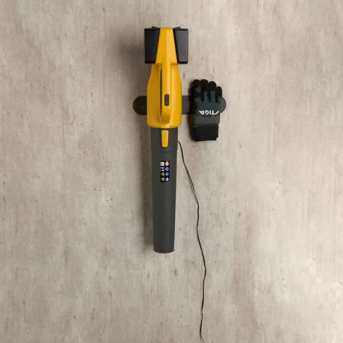 Żółto-czarna dmuchawa do liści na ścianie z rękawicą.