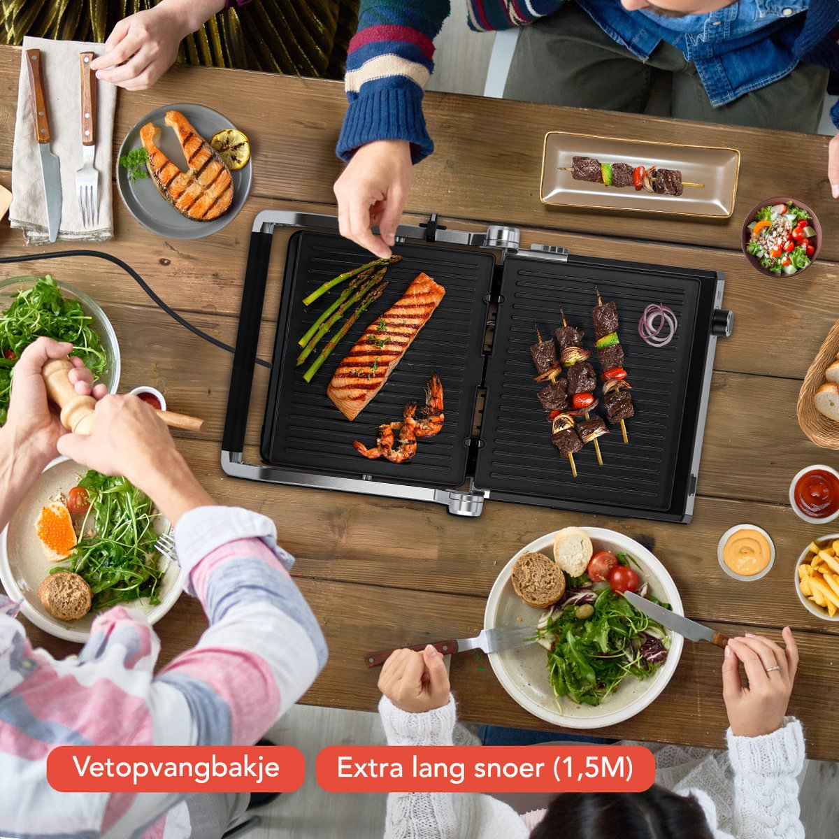 A table with food and people around it. A grill, salmon, shrimp, and vegetables are visible.