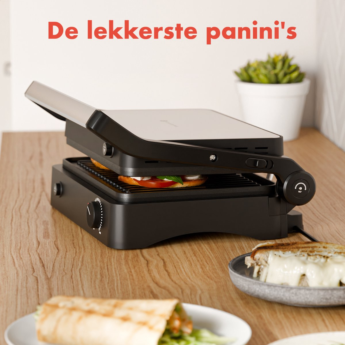 A black panini grill with a panini inside and a wrap and a sandwich on the table.