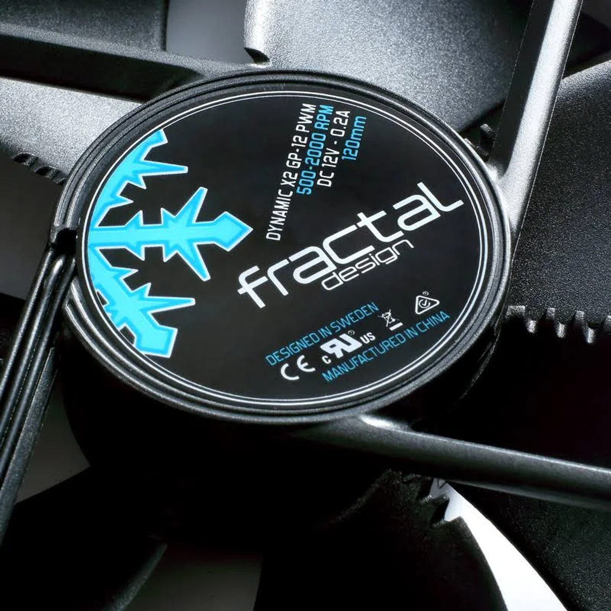 Nahaufnahme eines schwarzen Lüfters mit blau-weißem Logo. Das Logo sagt 'fractal design'. Der Lüfter hat schwarze Flügel.