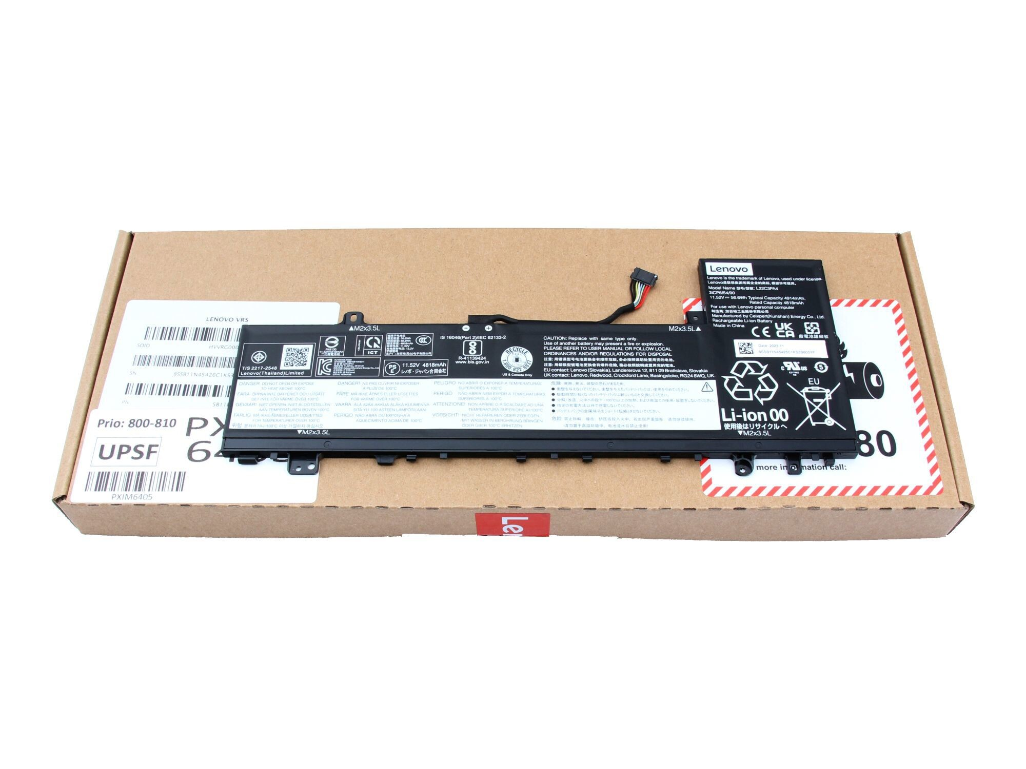 Laptop-Akku auf einem Karton. Ein schwarzer Akku mit Etikett liegt oben auf der Box.