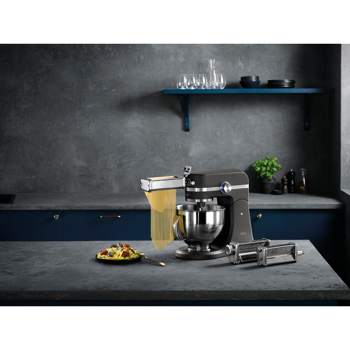 Un electrodoméstico de cocina, máquina de pasta, con un plato de pasta en la mesa.