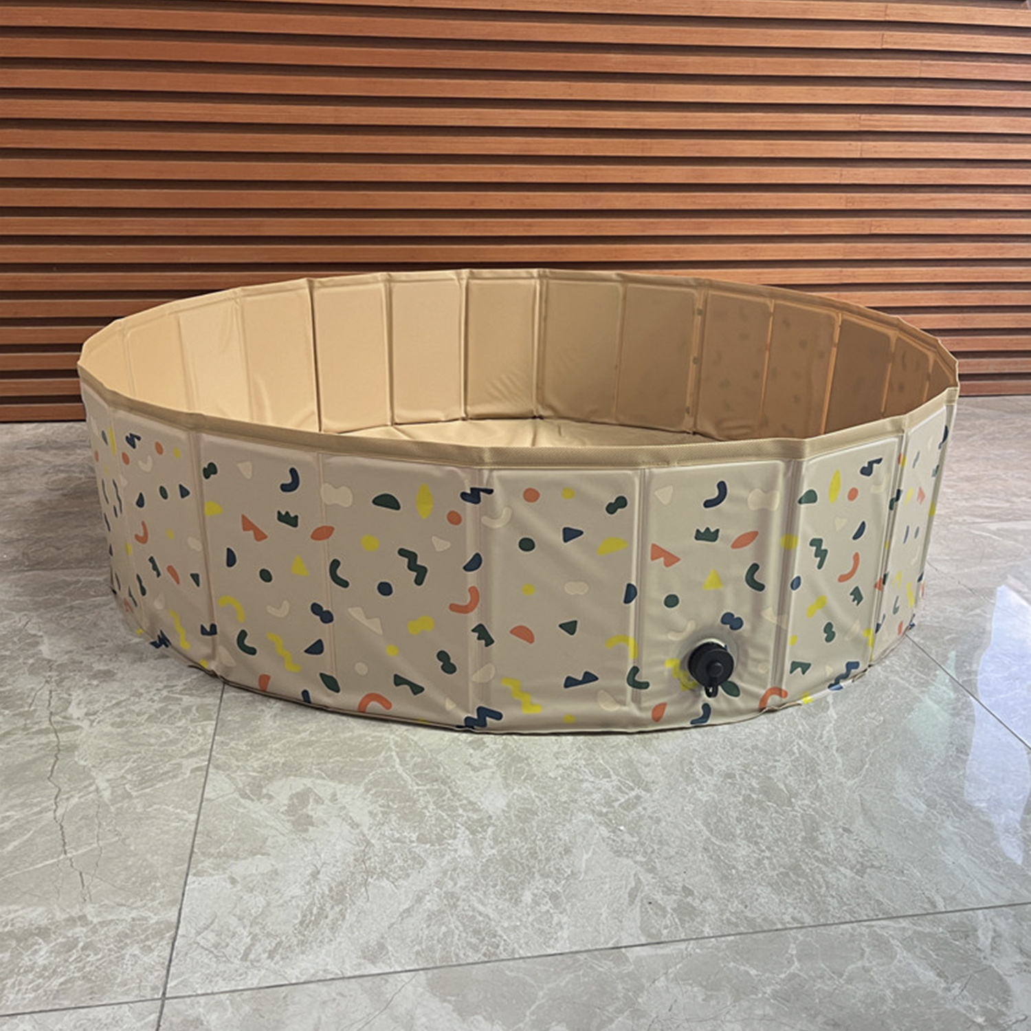 Una piscina beige, plegable y circular con formas coloridas.