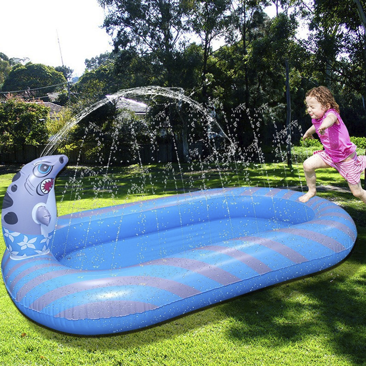 Bambino che gioca vicino a una piscina gonfiabile a tema squalo blu e grigia con spruzzo d'acqua.