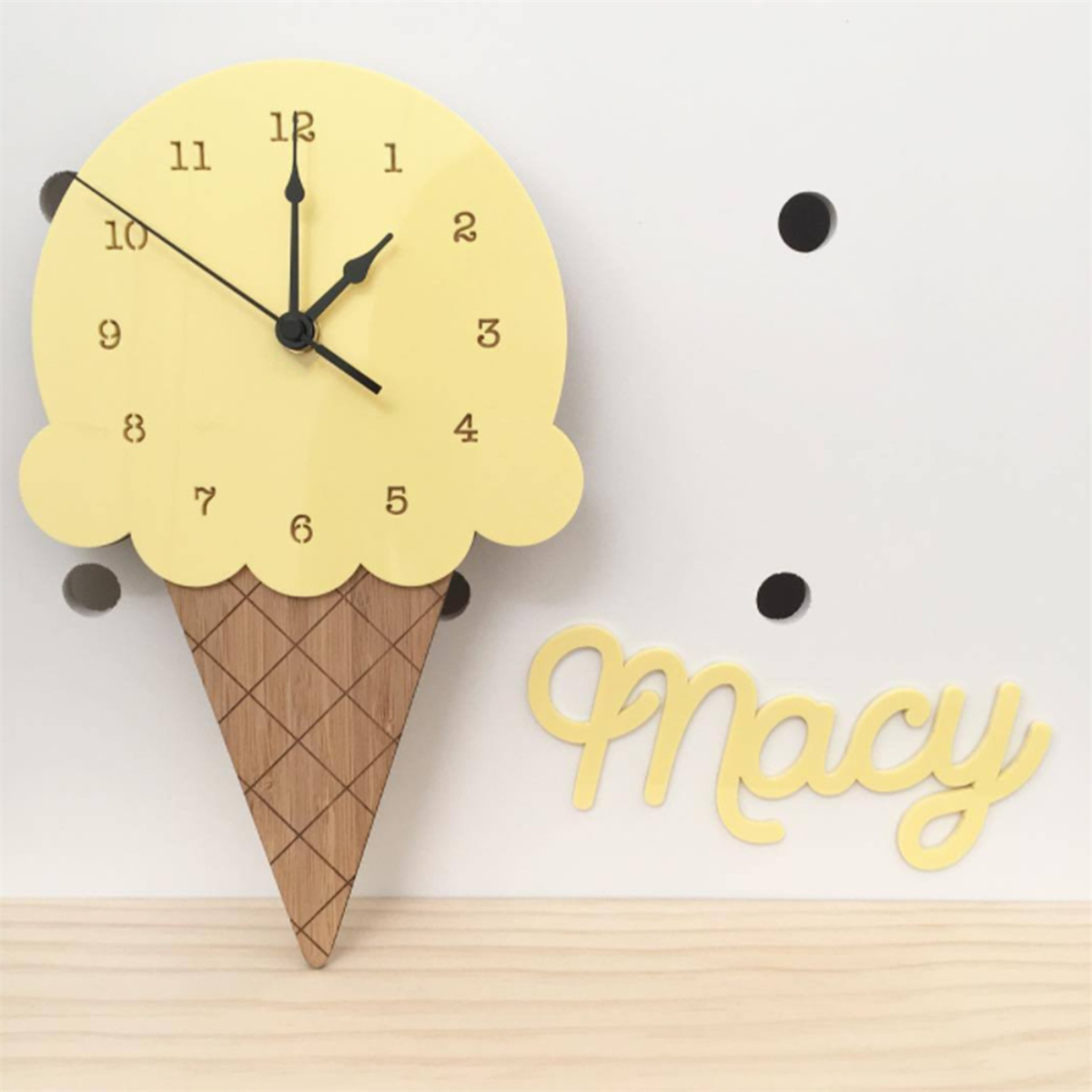 Eine eiscremeförmige Uhr. Die Uhr ist gelb mit schwarzen Zeigern und Zahlen. Der Name Macy steht unten.