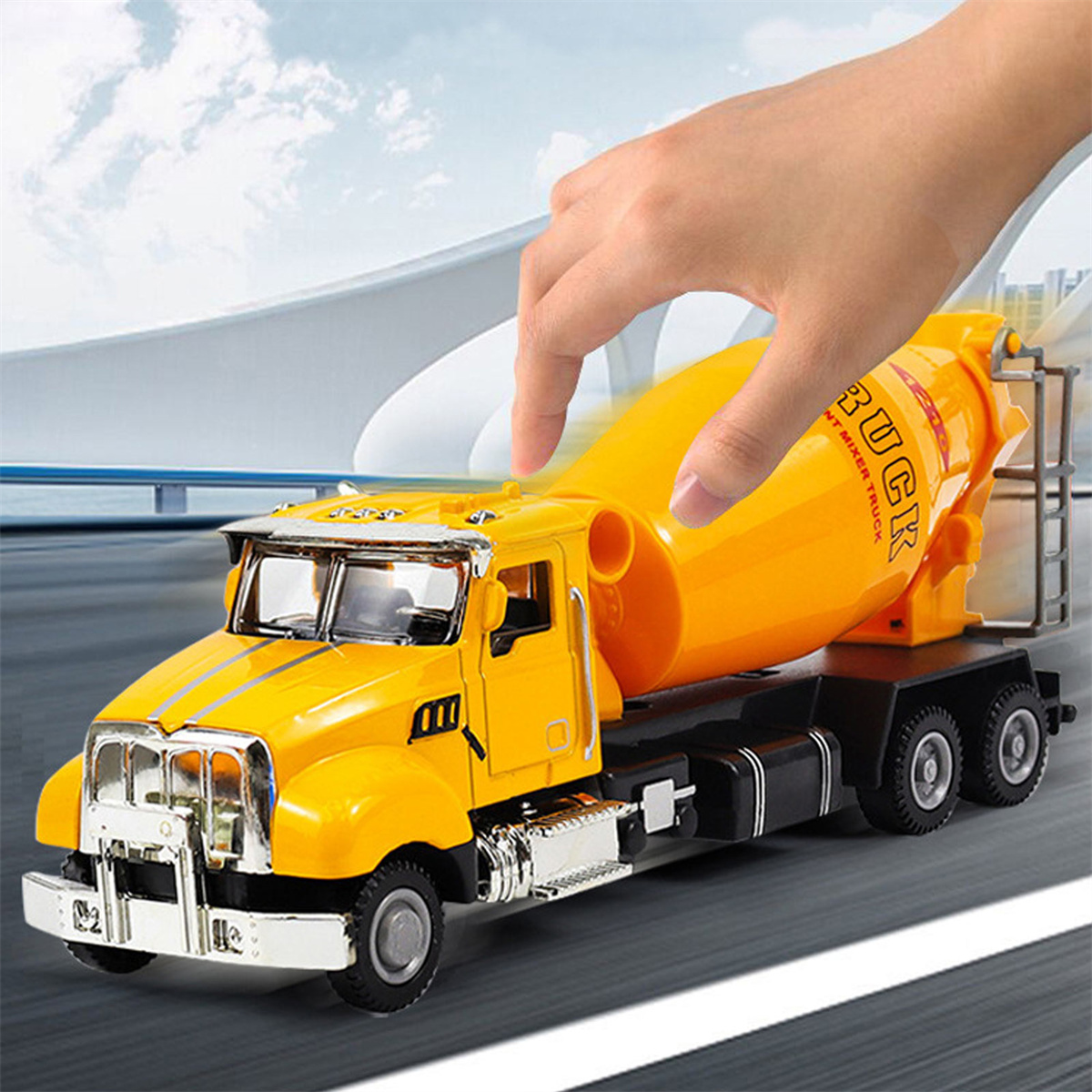Ein gelber Spielzeug-Zementmischer-LKW, der von einer Hand berührt wird.