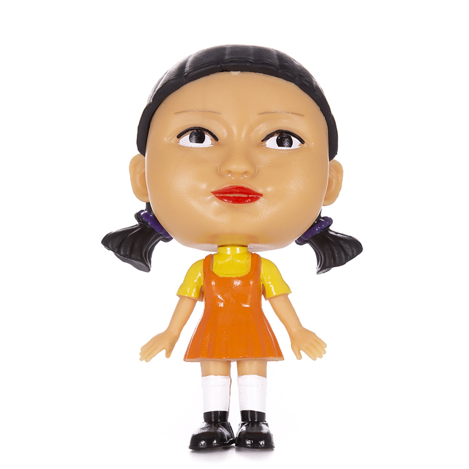 Figura de muñeca de Squid Game. Coletas rubias, vestido naranja, zapatos negros y labios rojos. Fondo blanco.