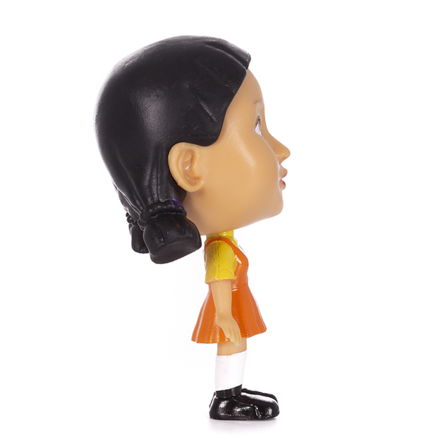 Vista lateral de la cabeza de una muñeca de El juego del calamar. La muñeca lleva un vestido naranja y zapatos negros.