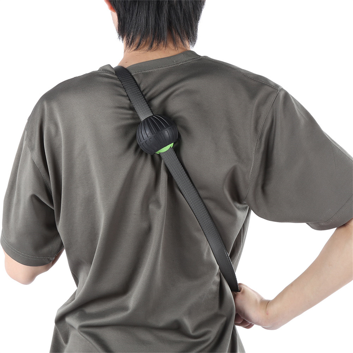 Person trägt graues Shirt mit Riemen und schwarzem Ball auf dem Rücken.