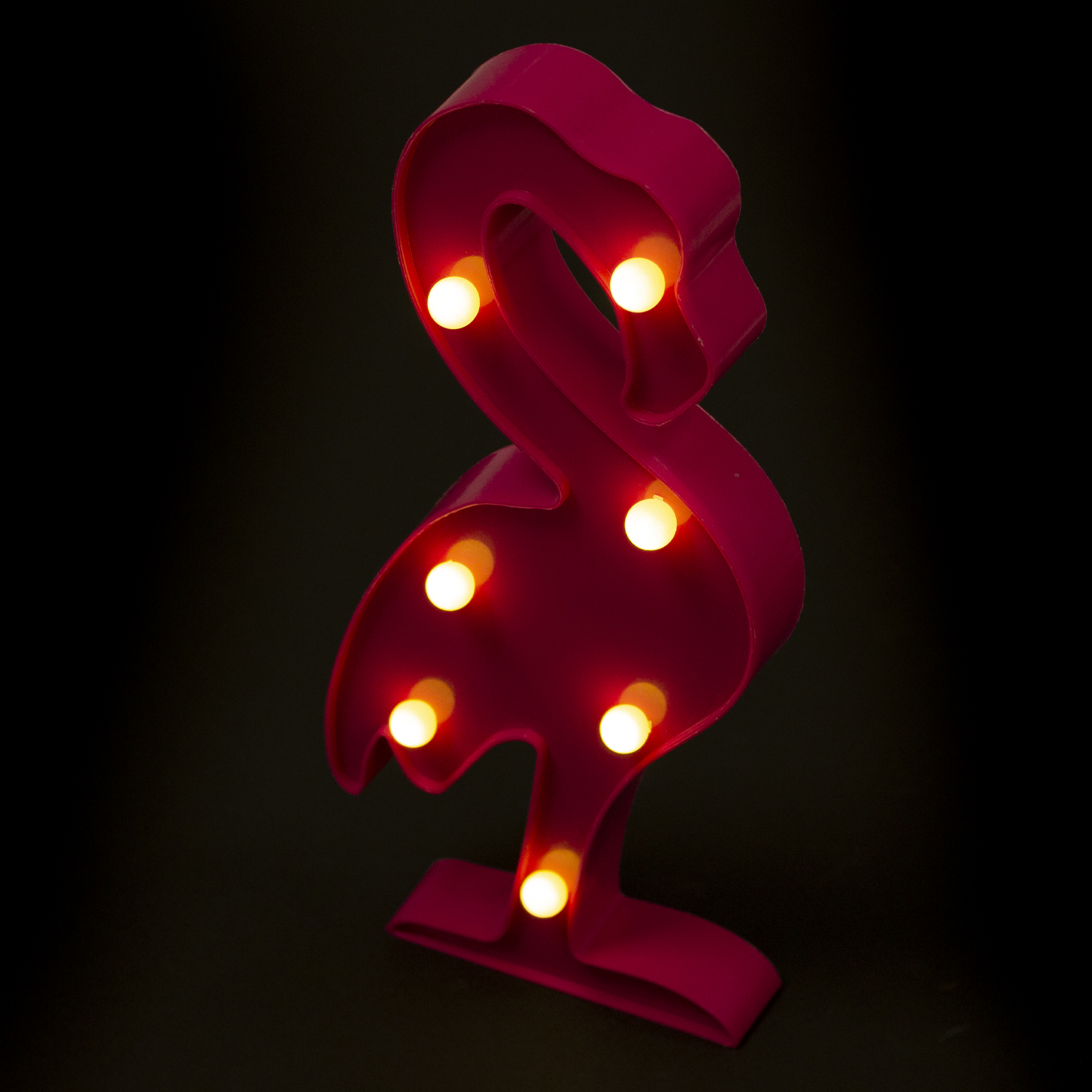 Luz en forma de flamenco rosa con bombillas iluminadas sobre fondo negro.