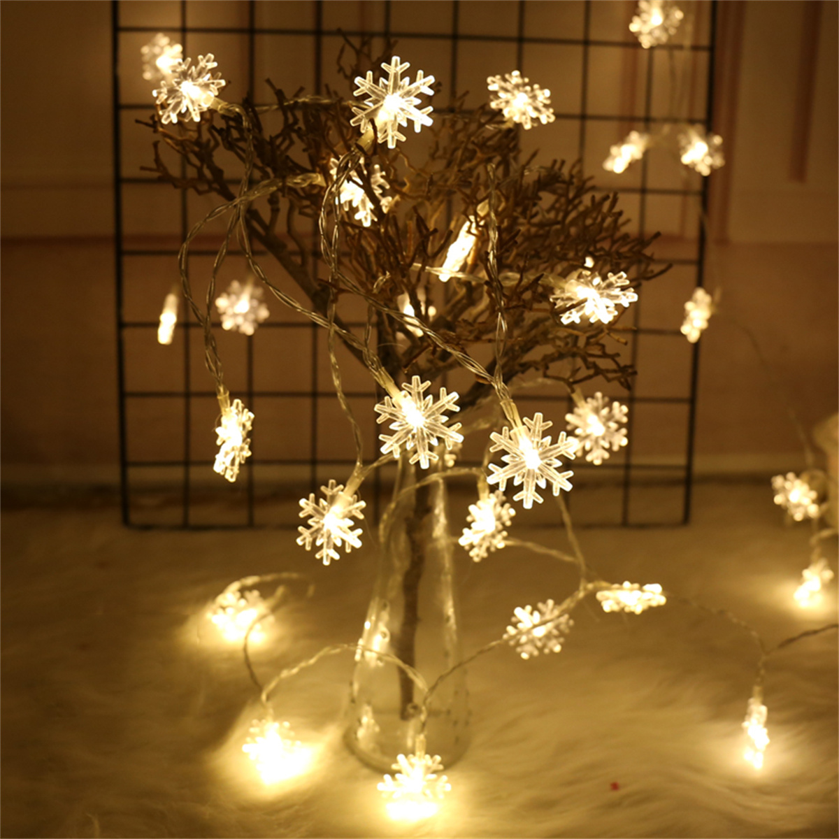 Schneeflockenlichter in einer Vase. Die Lichter beleuchten einen dunklen Hintergrund.