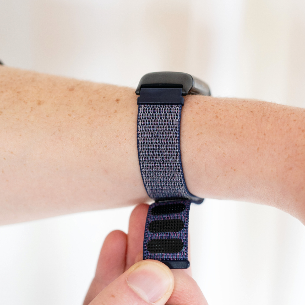 Handgelenk mit dunkelblauem Armband, Uhr befestigt. Hand justiert Armband.