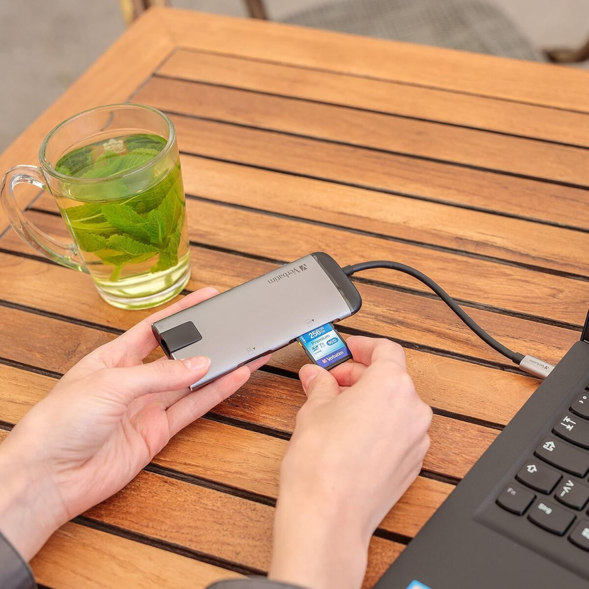 Srebrny hub USB podłączony do laptopa, z włożoną kartą pamięci.