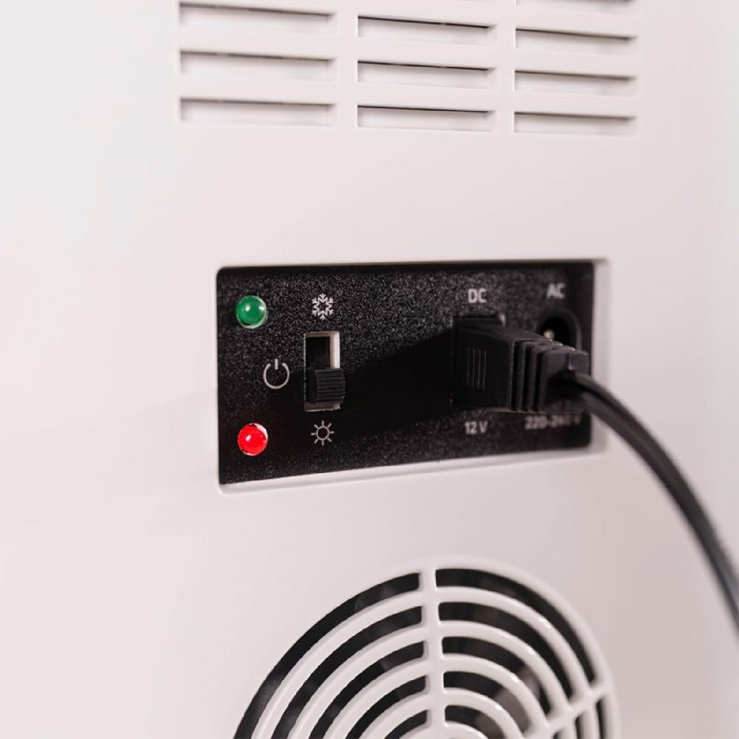 Primer plano de un panel de alimentación con interruptor, cable de alimentación y luces indicadoras sobre superficie blanca.