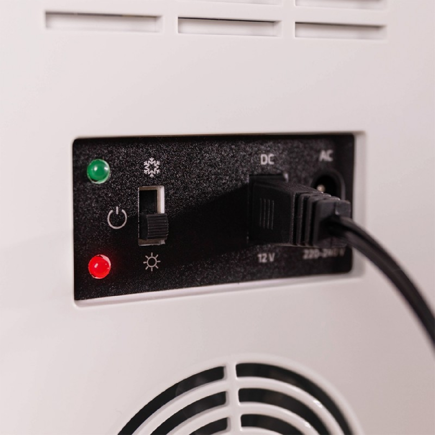 Primer plano de un panel de energía con un interruptor y luces indicadoras. Hay un cable de alimentación negro.