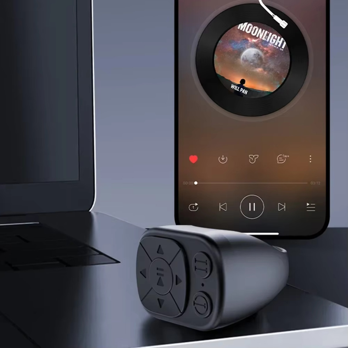Un control remoto negro en forma de anillo con botones, junto a un teléfono que muestra una aplicación de música.