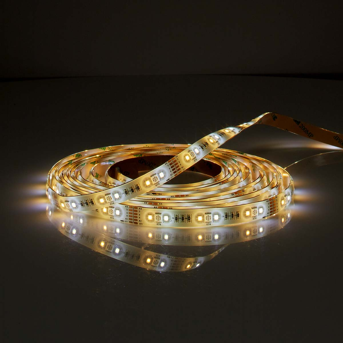 A coiled LED strip. The strip is flexible and lights up. It is on a dark surface.