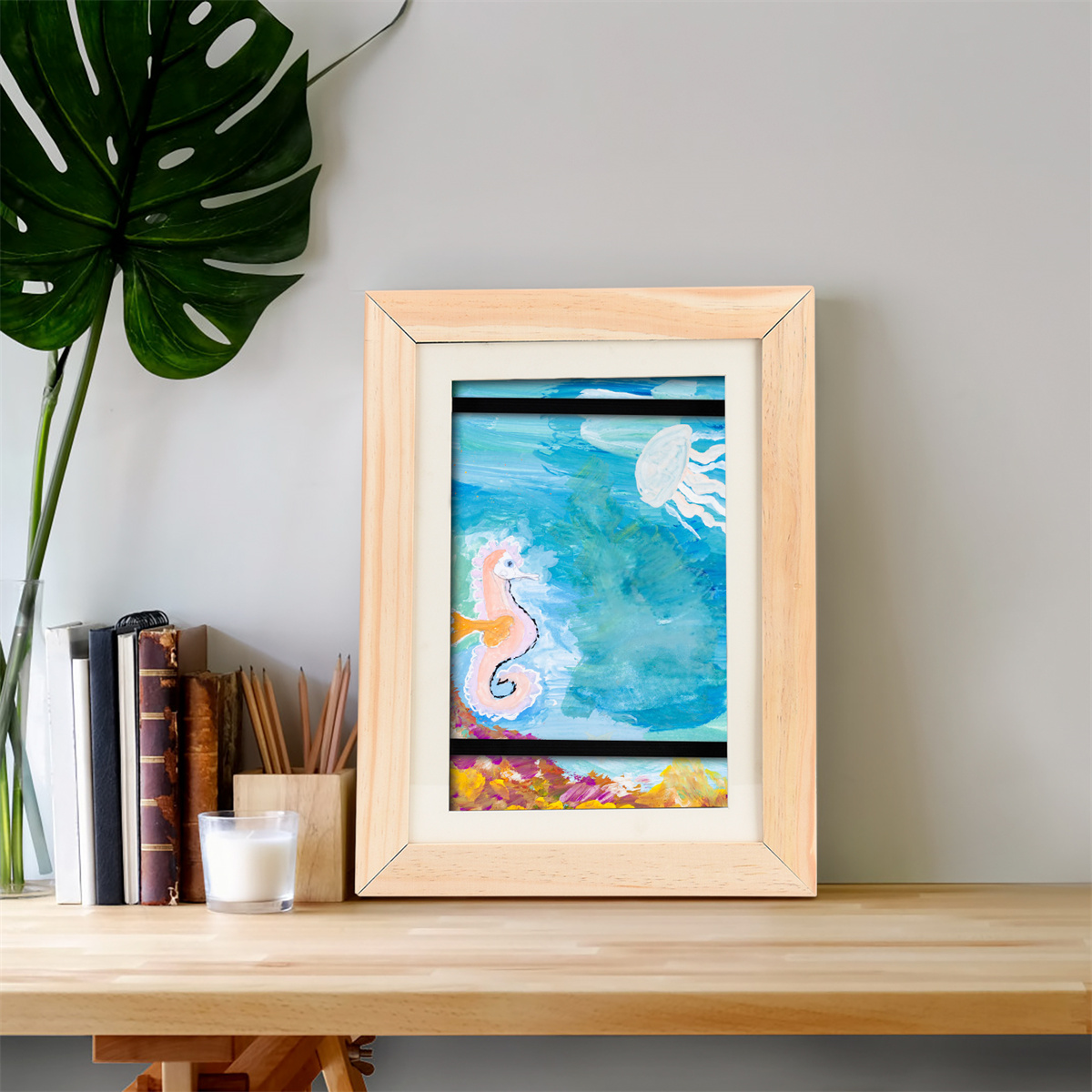 Kunstwerk in Holzrahmen. Ein Seepferdchen und eine Qualle sind in einer Meereslandschaft gemalt.