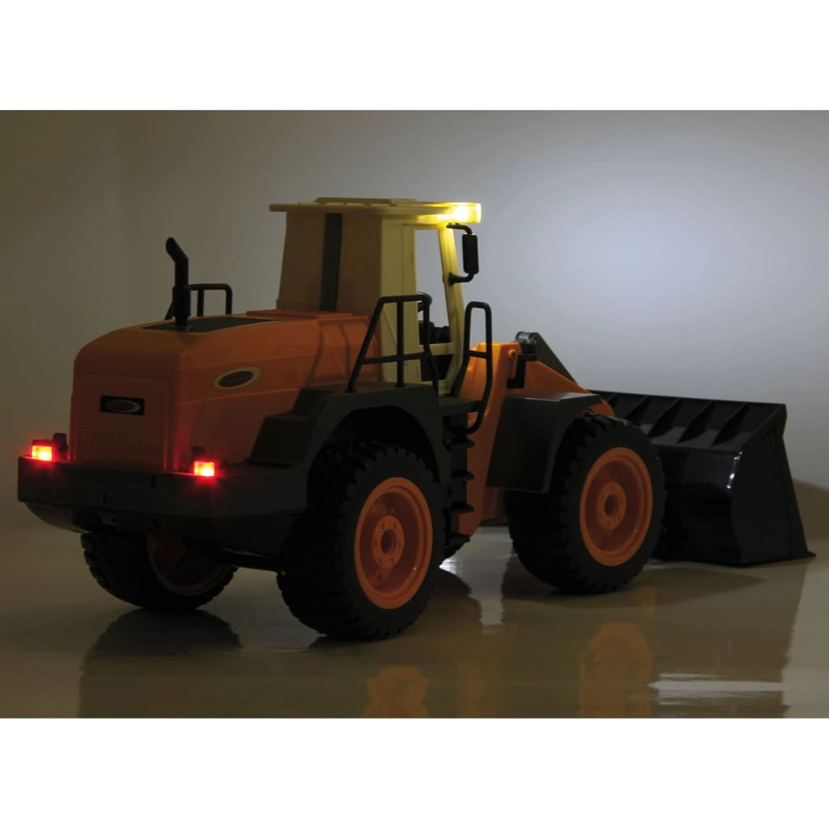 Pomarańczowo-czarny zabawkowy pojazd budowlany ze światłami, w słabo oświetlonym otoczeniu, z odblaskową powierzchnią.