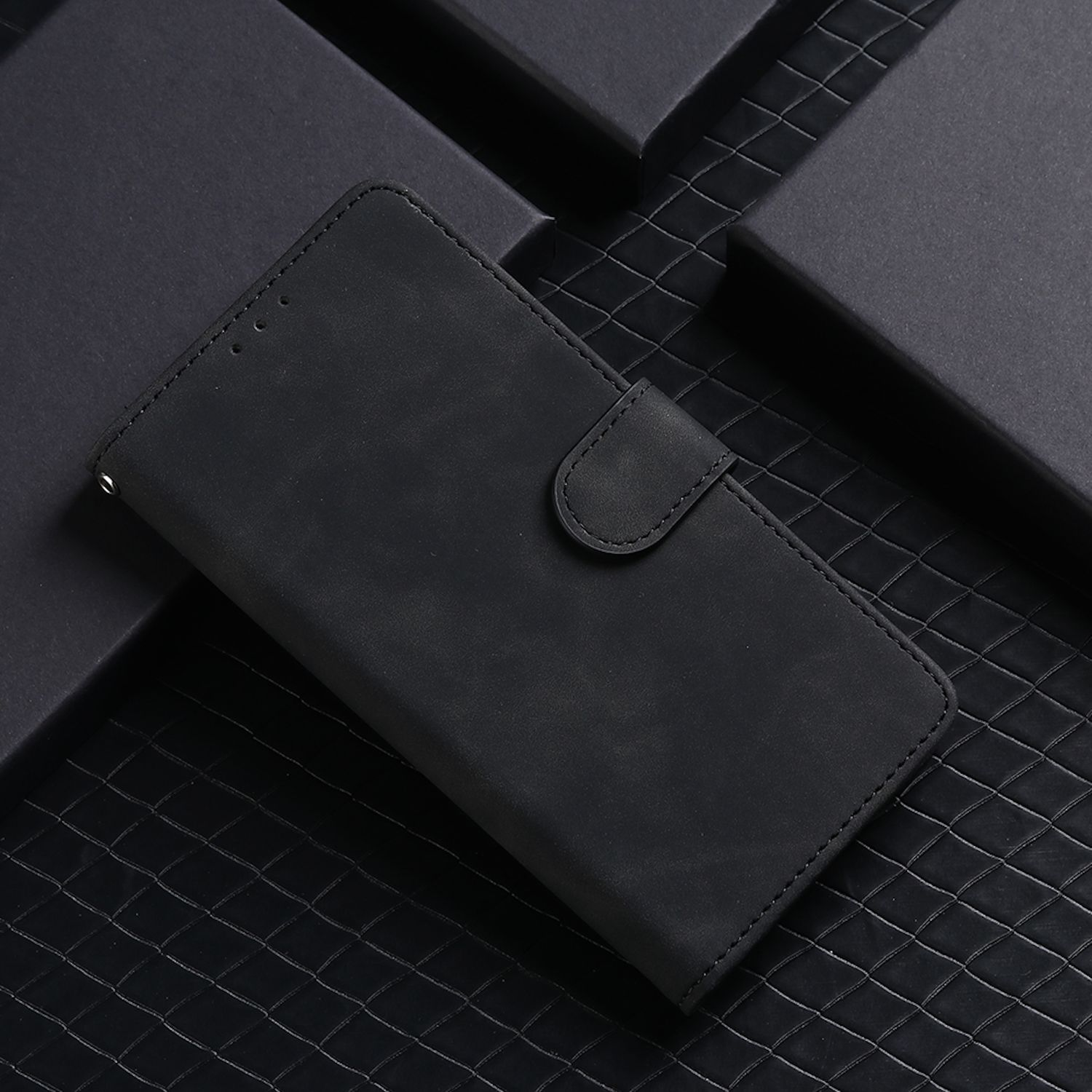 Schwarzes Leder-Telefon-Portemonnaie, geschlossen, auf einer strukturierten, dunklen Oberfläche mit schwarzen geometrischen Formen.