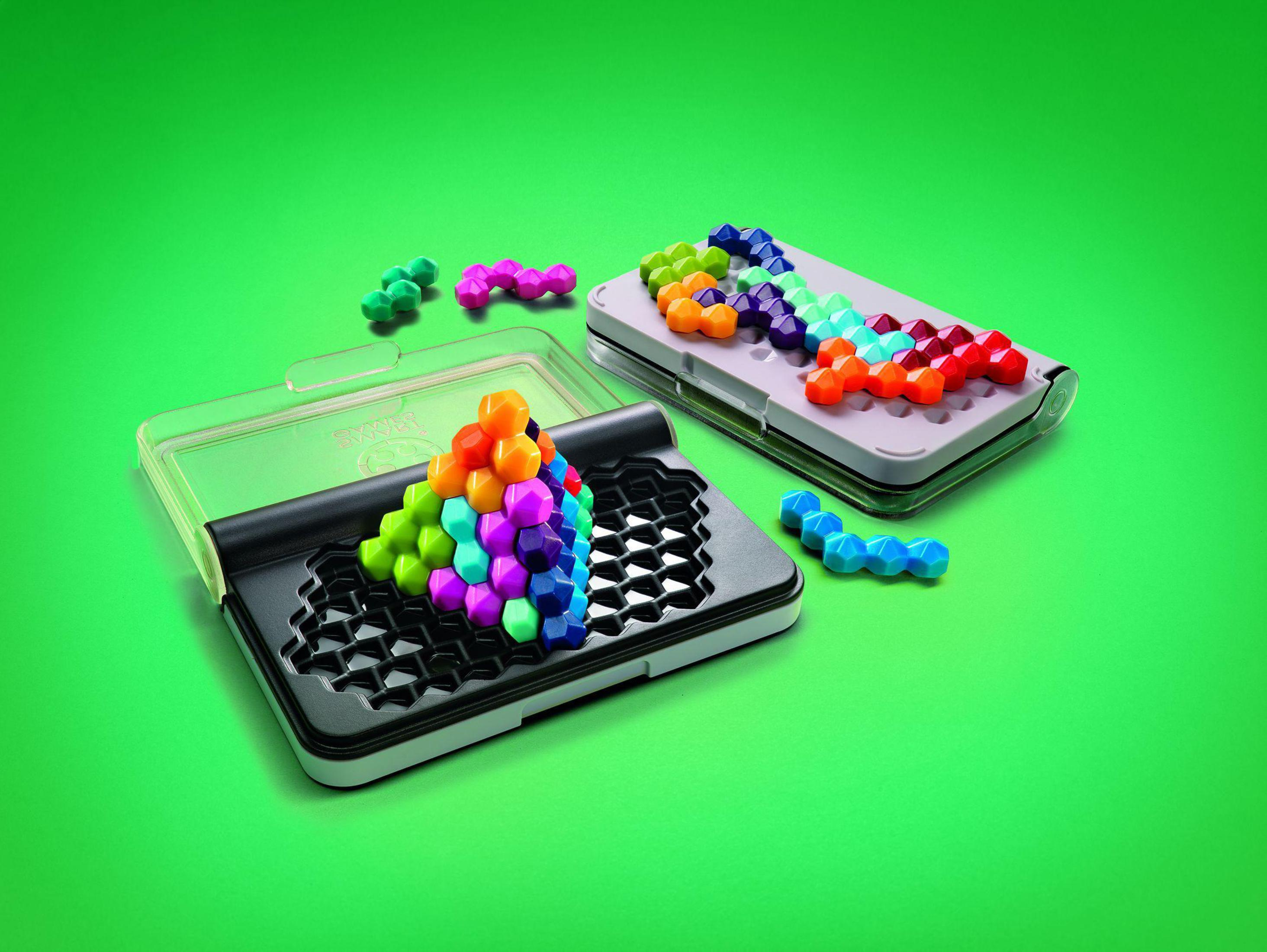 Pezi di puzzle colorati in una custodia, con coperchio aperto e pezzi sparsi su una superficie verde.