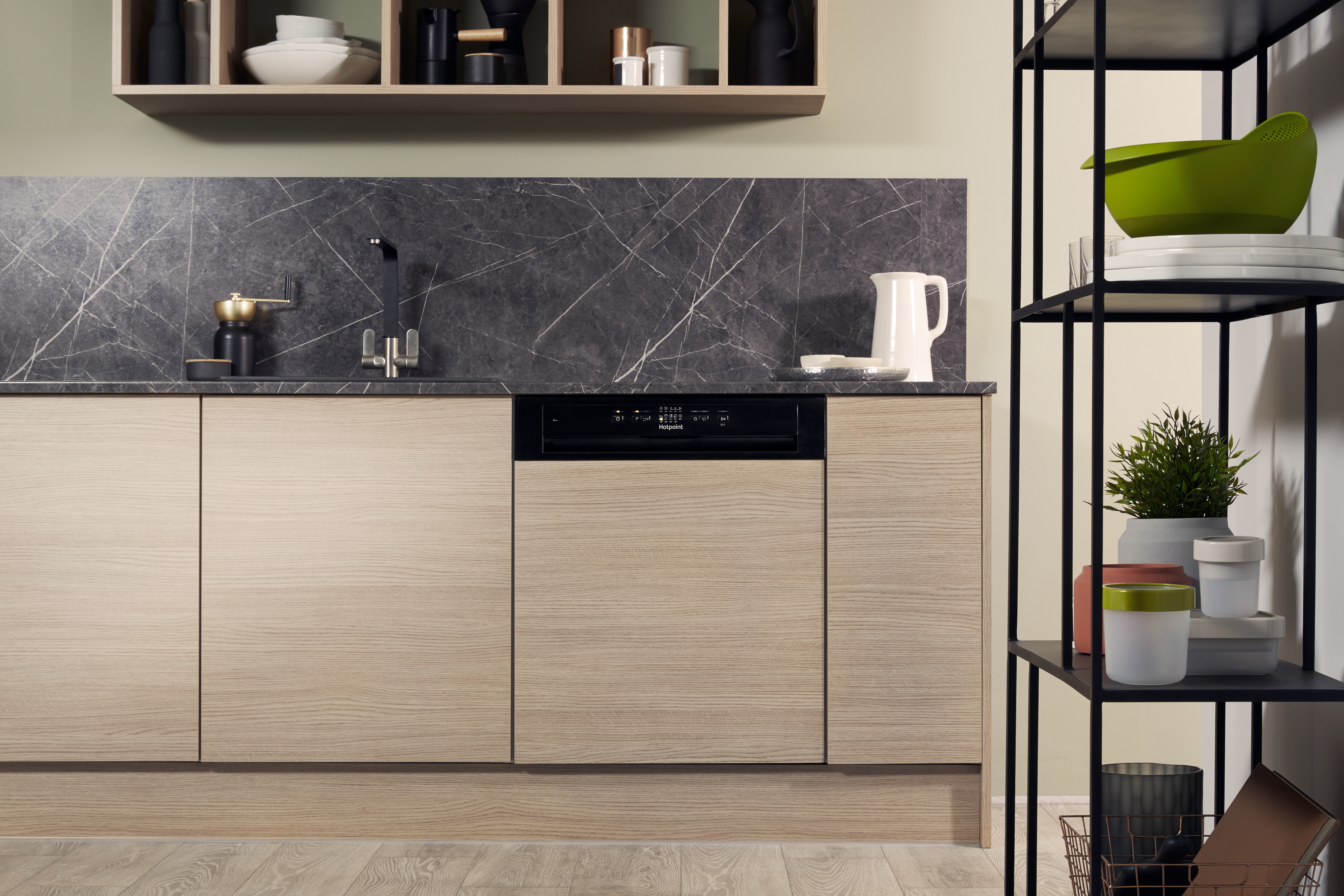 Cocina con gabinetes de madera, lavavajillas. Salpicadero de mármol negro y estantes con artículos.