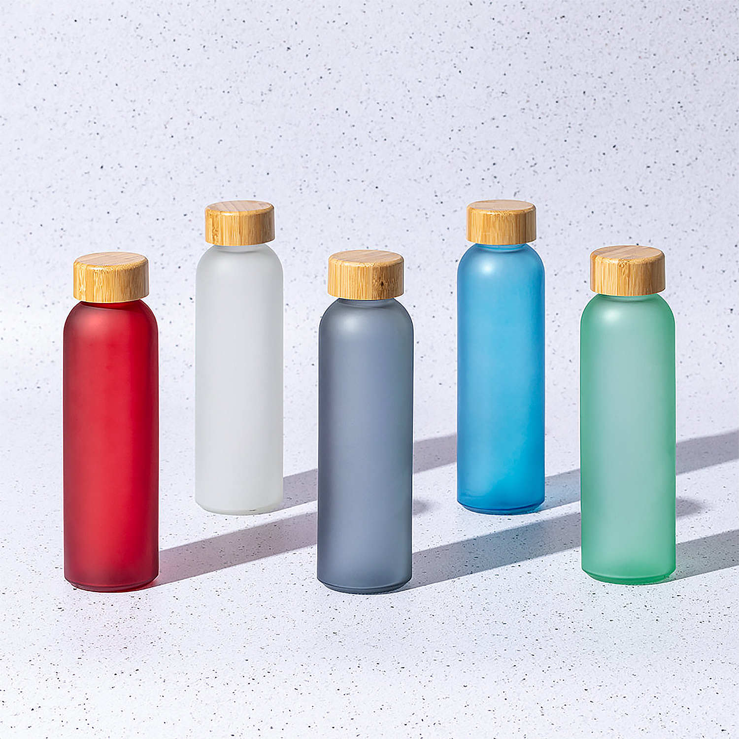 Cinque bottiglie d'acqua in vetro con coperchi in legno, ciascuna di un colore diverso: rosso, bianco, grigio, blu e verde.