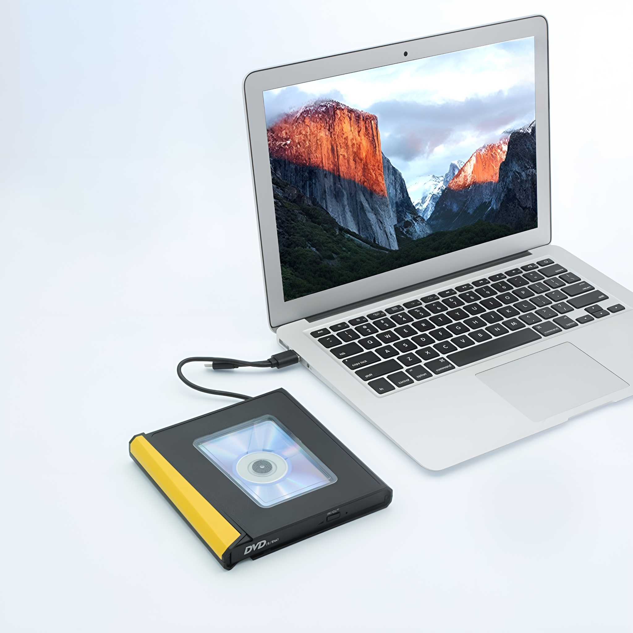 Ein Laptop ist mit einem DVD-Lesegerät auf einer weißen Oberfläche verbunden. Eine DVD befindet sich im Lesegerät.