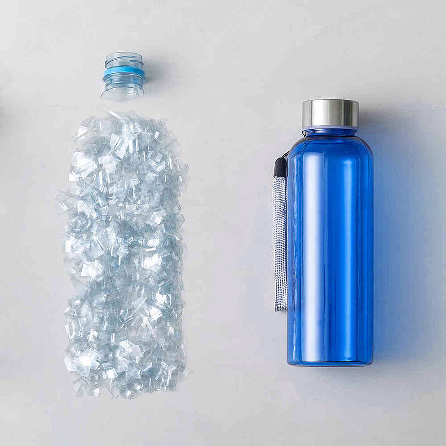 Botella de agua azul junto a un montón de trozos de plástico, mostrando un concepto de reciclaje.