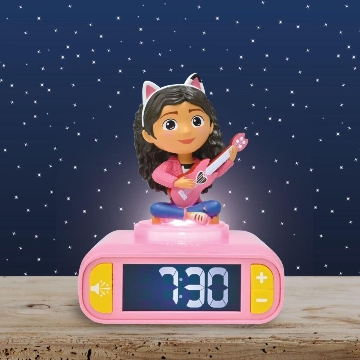 Reloj despertador rosa con una niña de dibujos animados tocando la guitarra, contra un cielo estrellado.