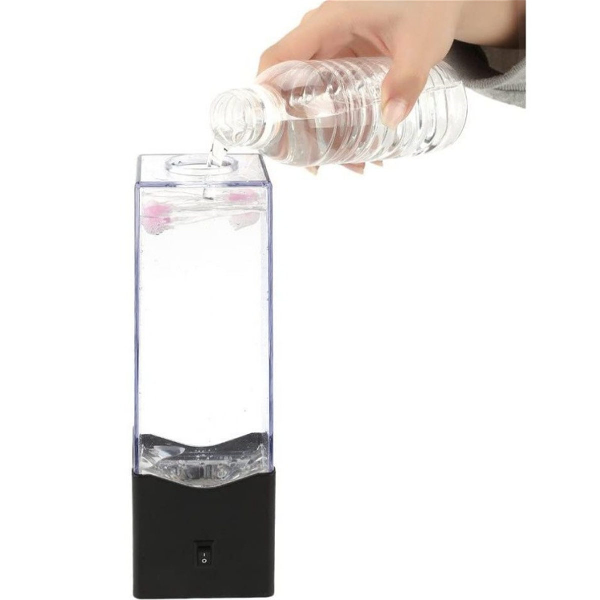 Eine Hand gießt Wasser in einen durchsichtigen Behälter mit schwarzem Boden. Der Behälter hat Blasen im Inneren.