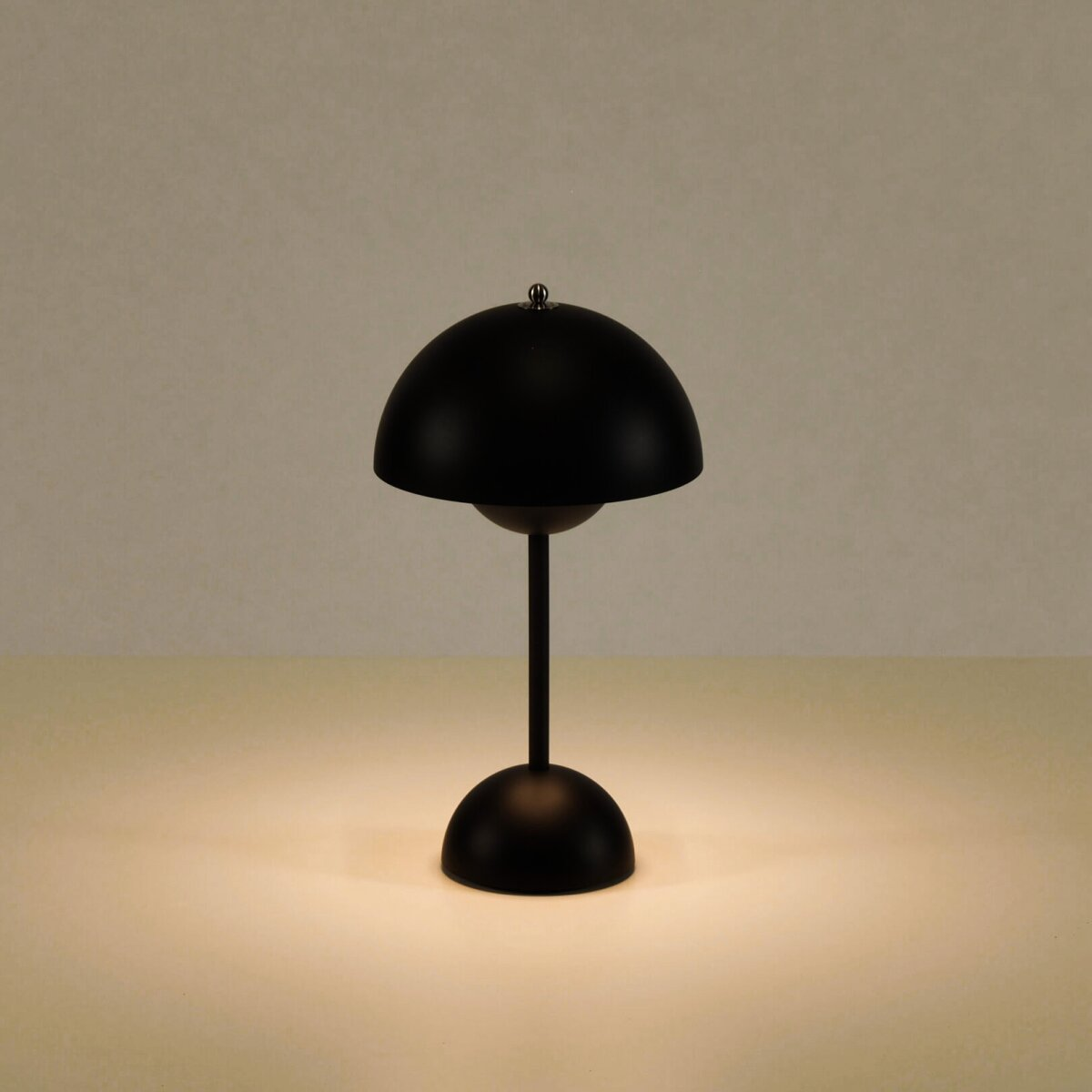 Eine schwarze, kuppelförmige Tischlampe auf einer hellbeigen Oberfläche.