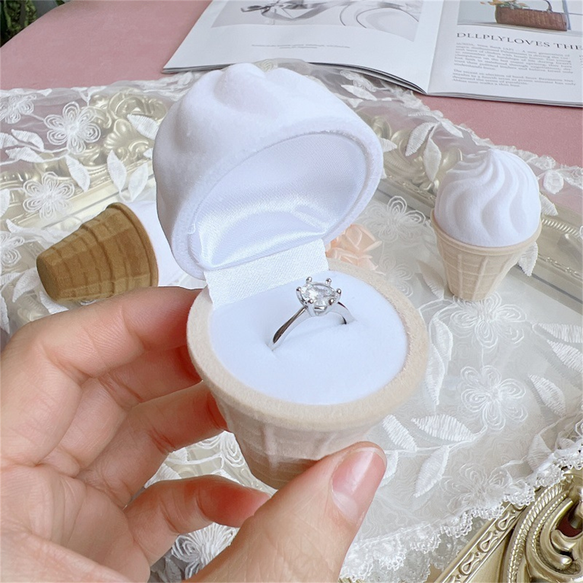 Ring in einer eiscreme-förmigen Schachtel. Die Schachtel ist weiß mit einem braunen Kegel.