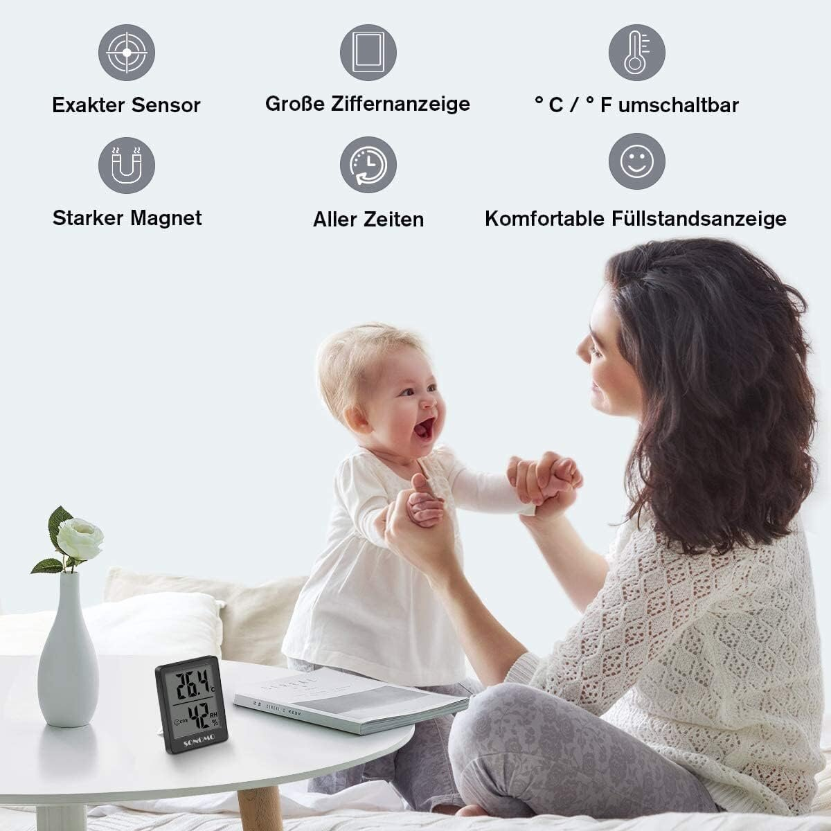 Eine Frau und ein Baby. Auf einem Tisch liegt ein Thermometer mit Text. Das Baby lächelt.