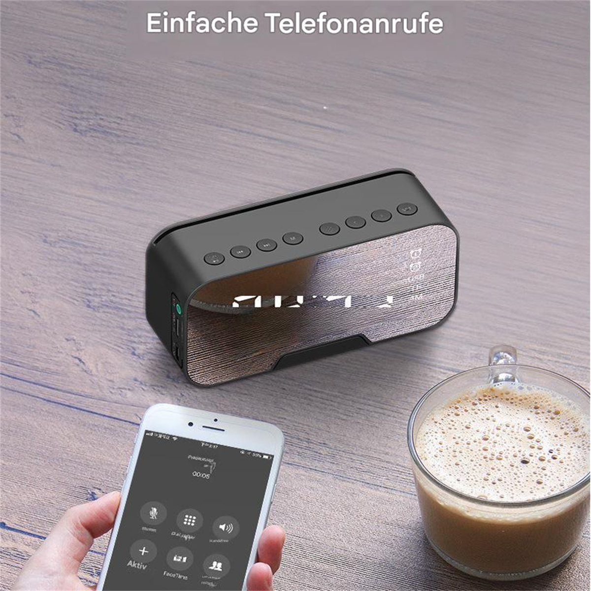Schwarzer Lautsprecher mit Tasten, Telefon mit Oberfläche und Kaffeetasse auf dem Tisch.