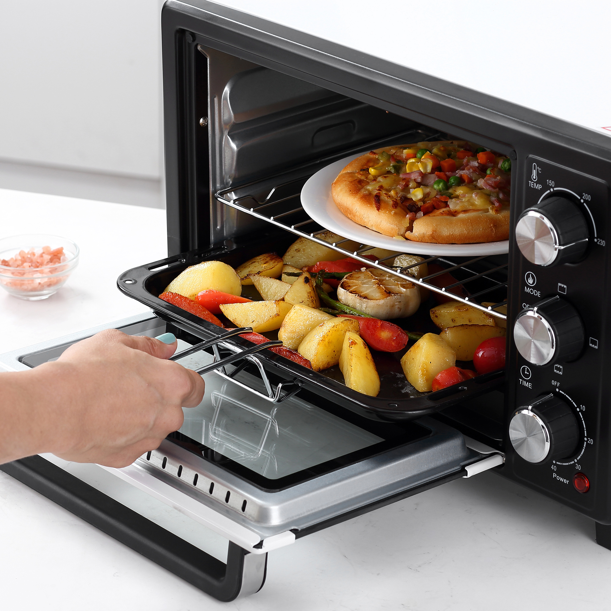 Un forno con una pizza sopra e verdure arrostite all'interno.