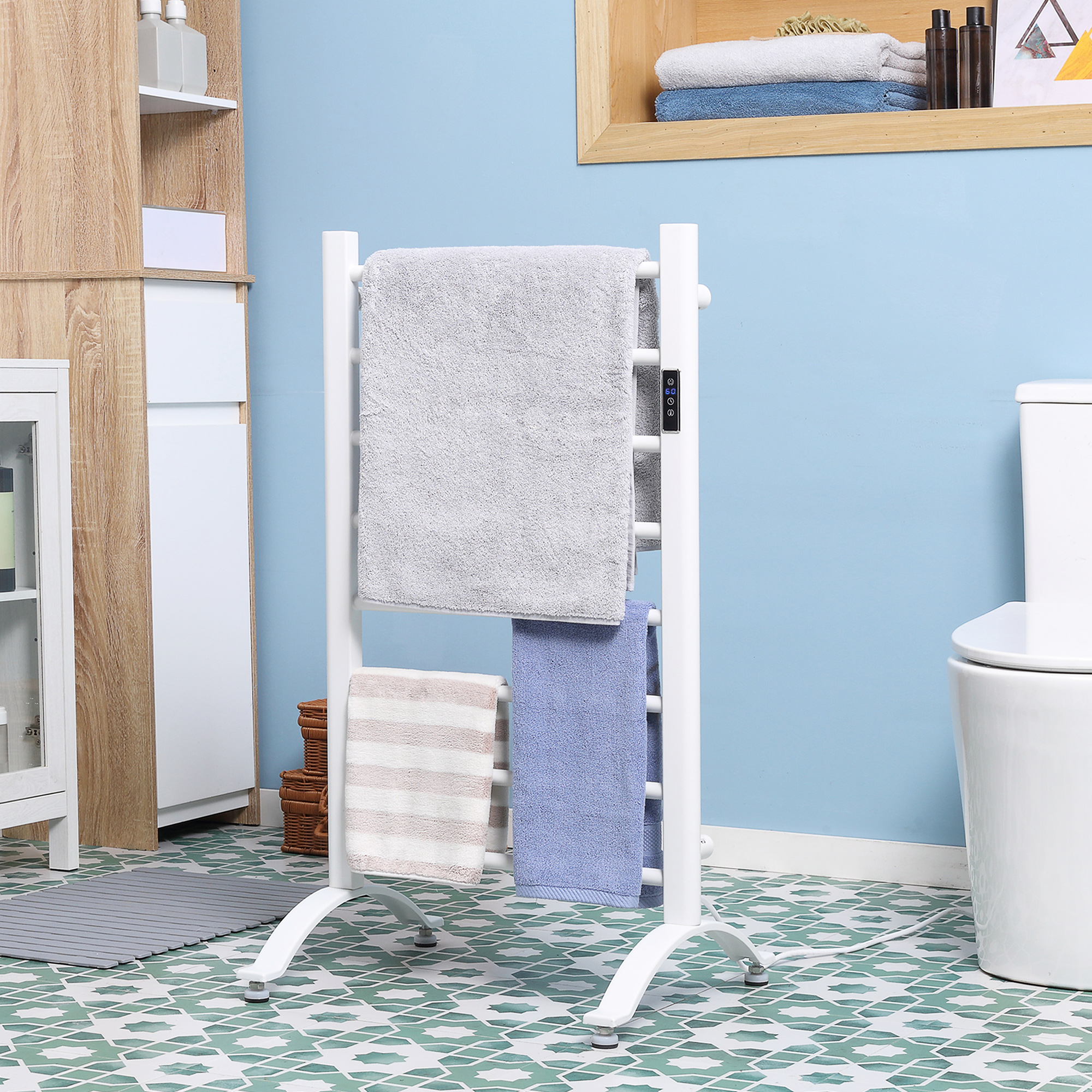 Un scaldasalviette bianco con asciugamani grigi, blu e a strisce appesi contro un muro blu.